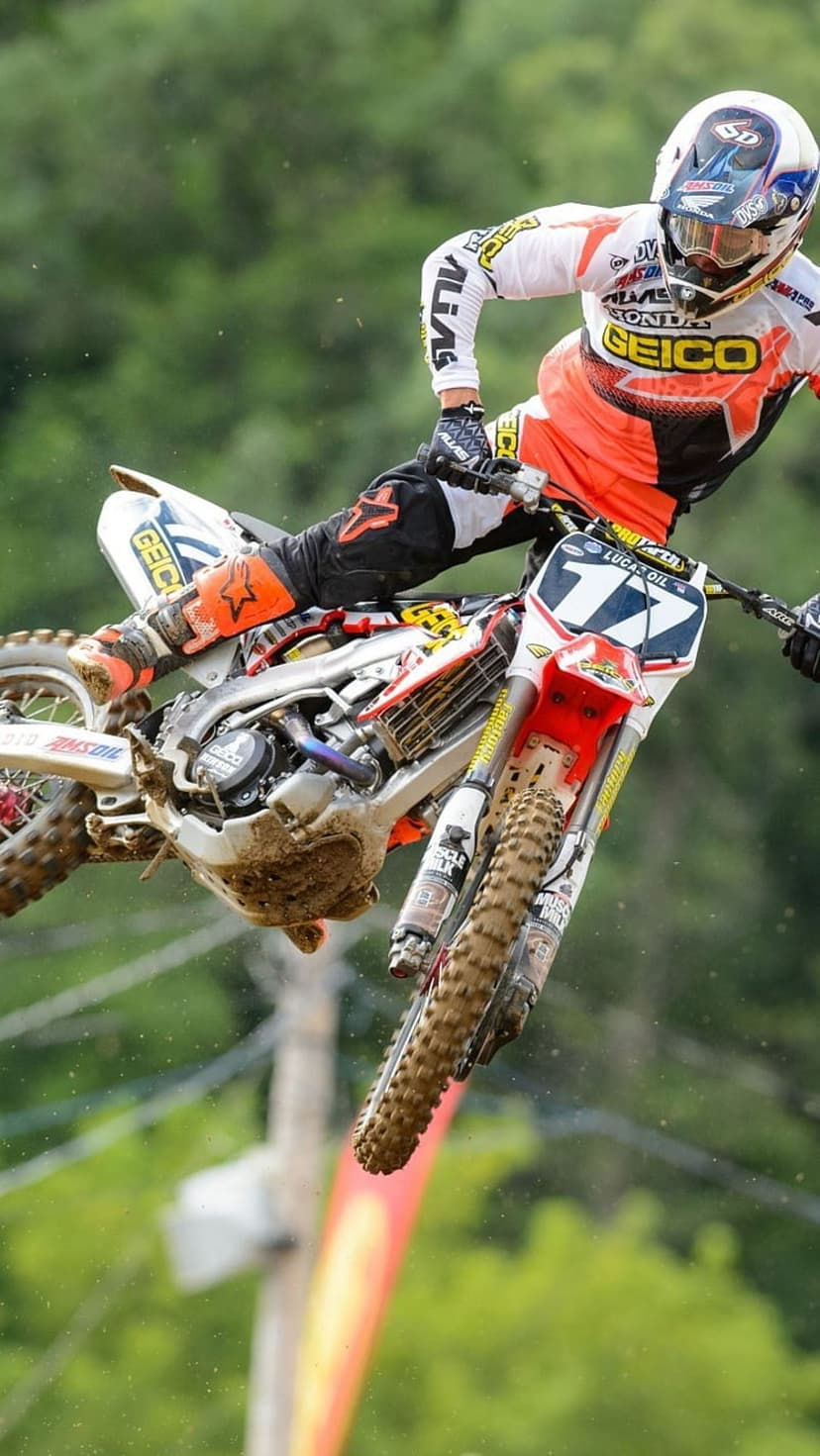 Motocross rider in mid-air jump on a dirt bike against a soft green background for a vertical screen display.