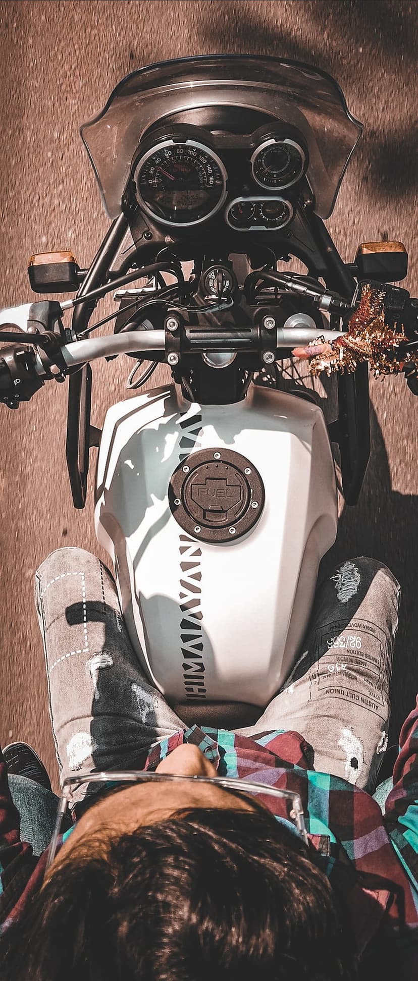 Royal Enfield Himalayan motorcycle rider wearing denim and plaid viewed from a first-person perspective on a road.