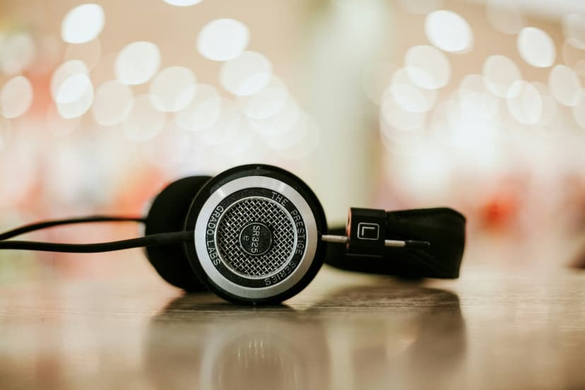 Black Grado headphones with metallic grilles on a wooden table under soft, golden background bokeh lights.