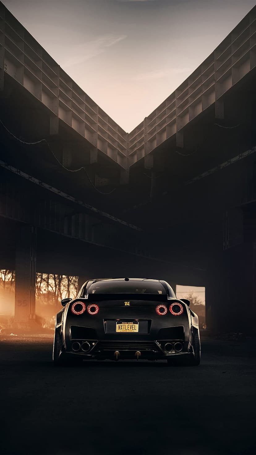 Nissan GT-R rear view with glowing red taillights inside a dark concrete tunnel with hazy orange lighting.