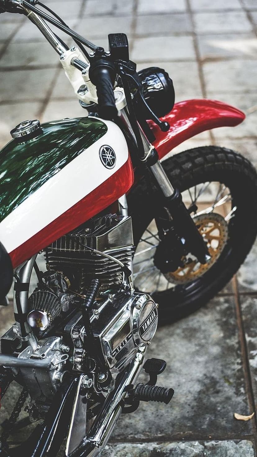 Vintage Yamaha motorcycle with a green and white fuel tank, chrome engine parts, and black knobby tires.