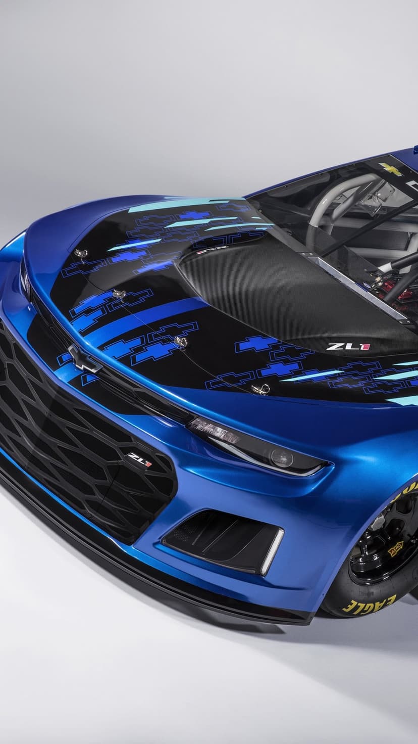 Close-up of a blue Chevrolet Camaro ZL1 race car with a patterned black hood and yellow tire lettering.