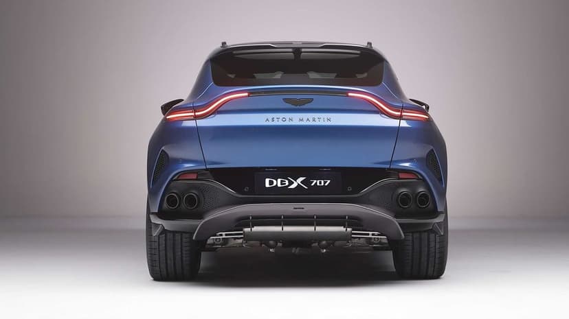 Rear view of a metallic blue Aston Martin DBX707 with quad exhausts and a thin red LED taillight bar.