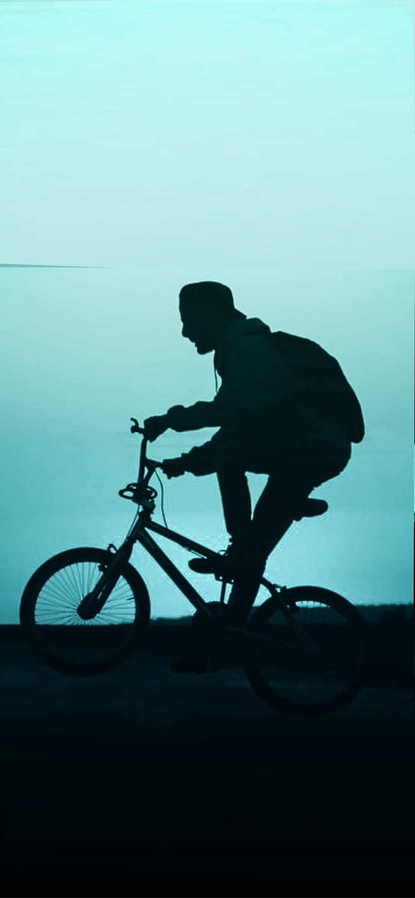 BMX cyclist in silhouette performs an aerial trick against a vast, bright cyan sky with a soft color gradient.
