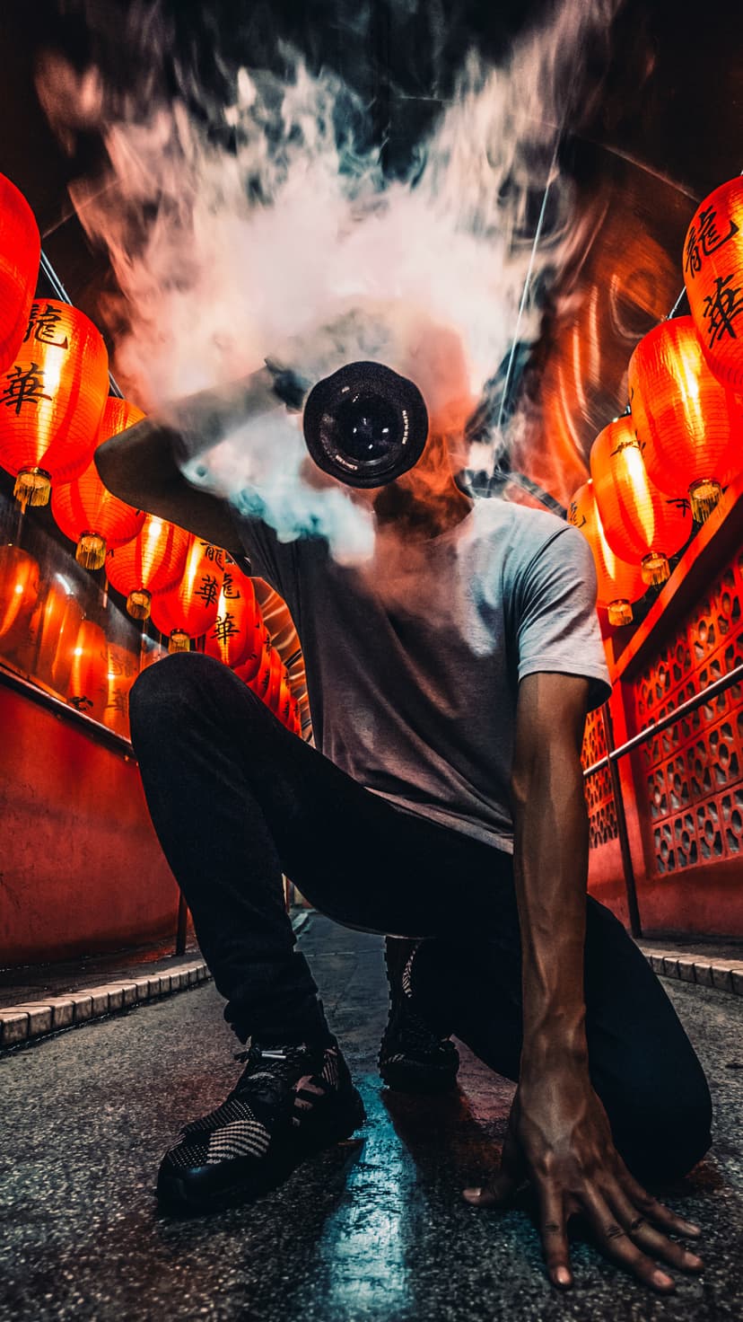 Person exhales thick white smoke while standing in a narrow hallway decorated with glowing red Chinese lanterns.