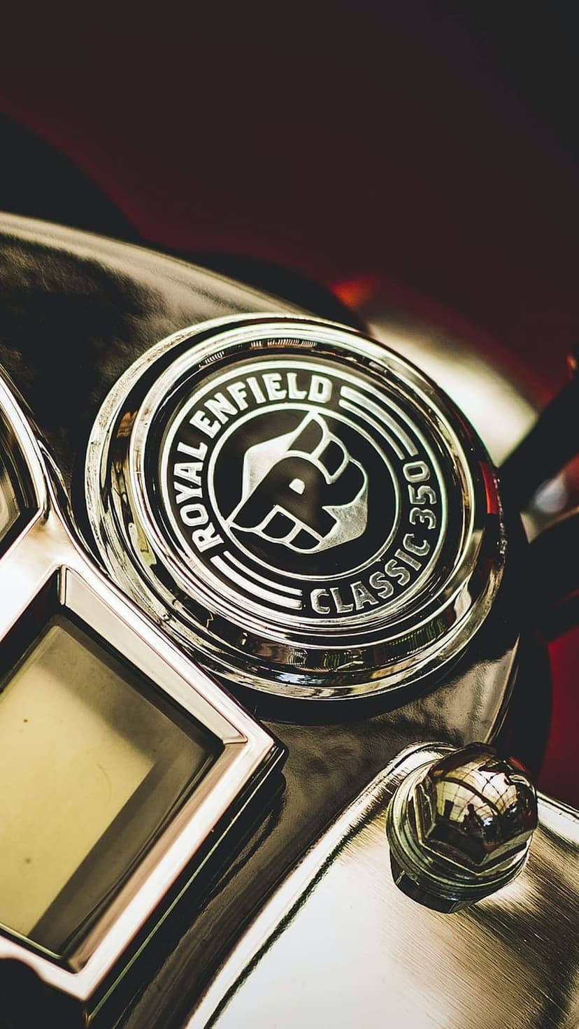 Royal Enfield Classic 350 chrome emblem and metallic instrument panel reflecting light on a vintage motorcycle.
