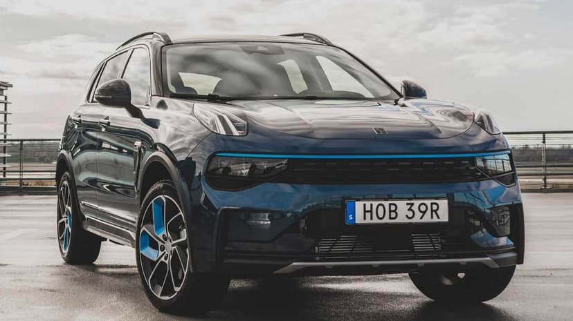 Metallic blue SUV with cyan accents on wheels and grille parked on an urban rooftop under an overcast sky.