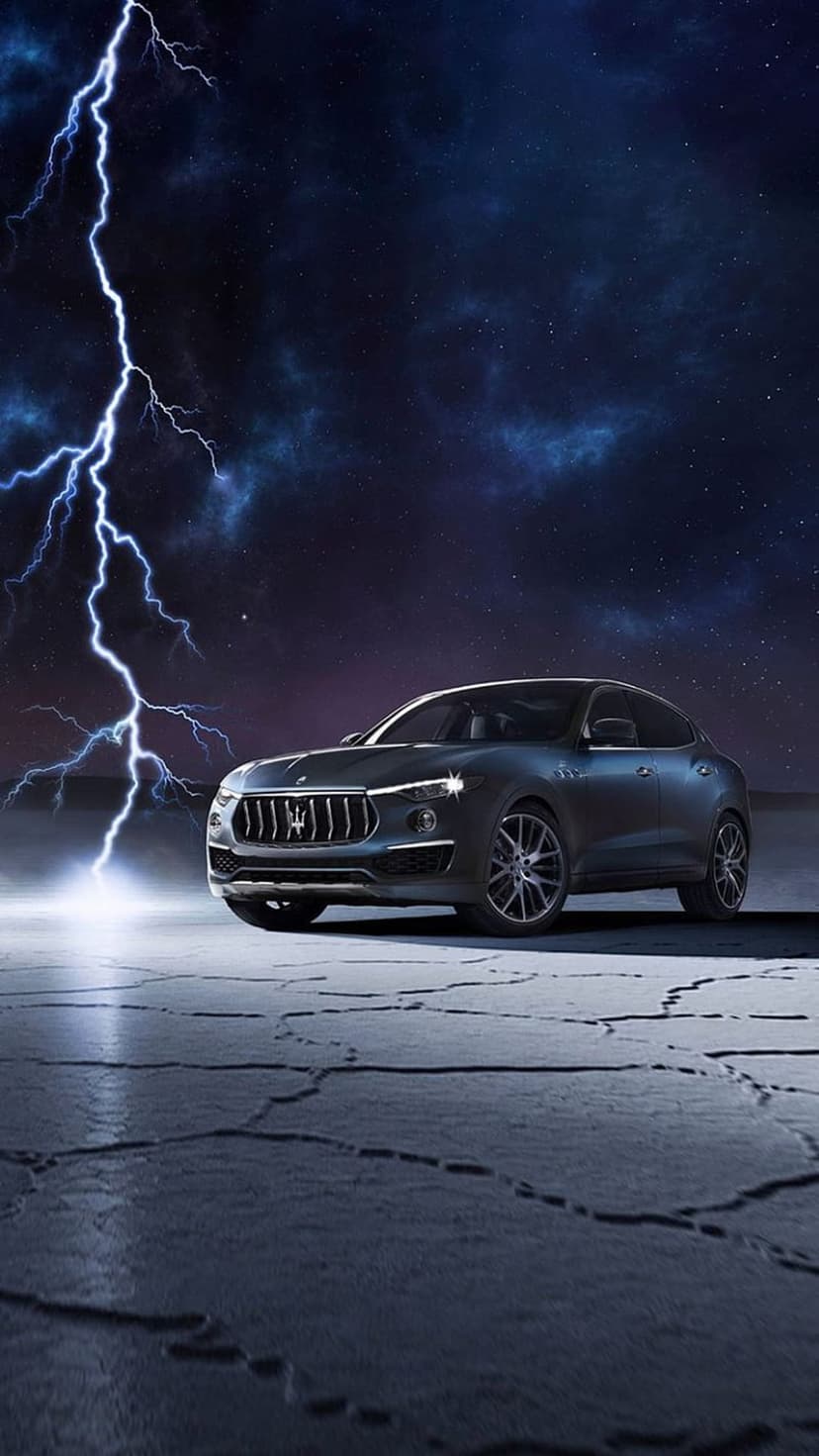 Maserati Levante SUV parked on cracked ground during a nighttime thunderstorm with a large lightning strike.