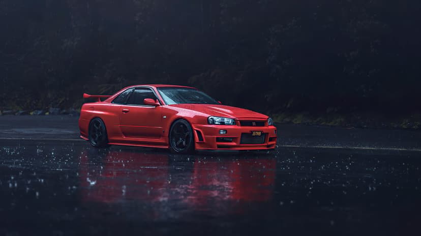 Red Nissan Skyline GT-R R34 parked on a wet, rainy road at night with dark forest background reflections.