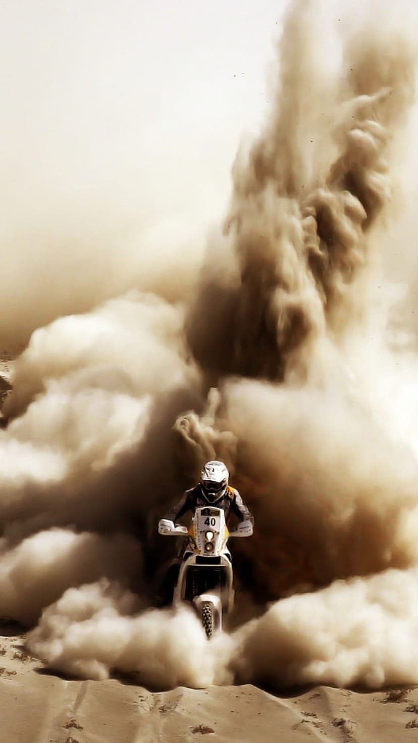 Motorcyclist wearing gear number forty surges through a massive, swirling cloud of brown desert sand and dust.
