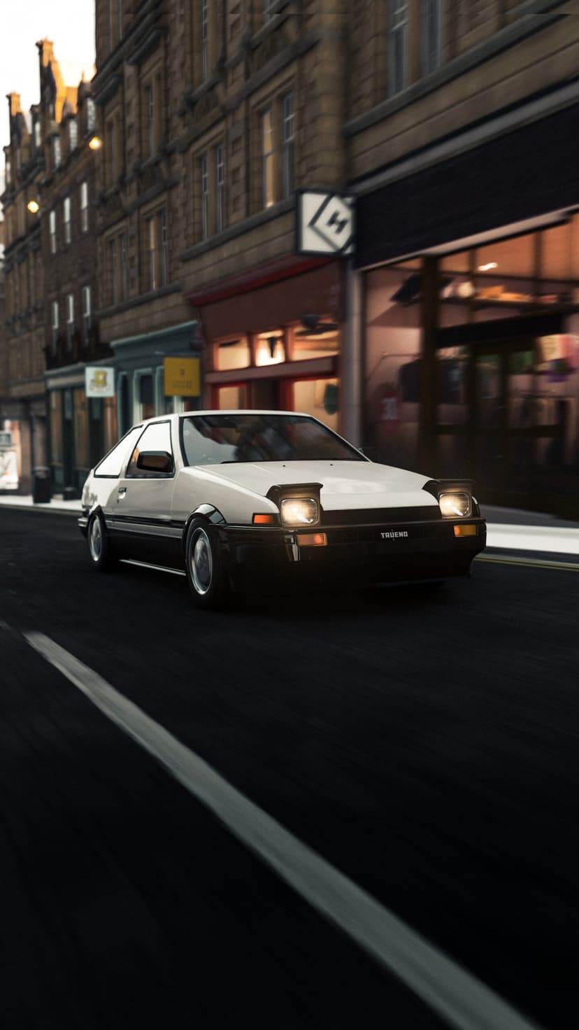 White and black Toyota AE86 driving on a city street at night with glowing headlights and motion blur.