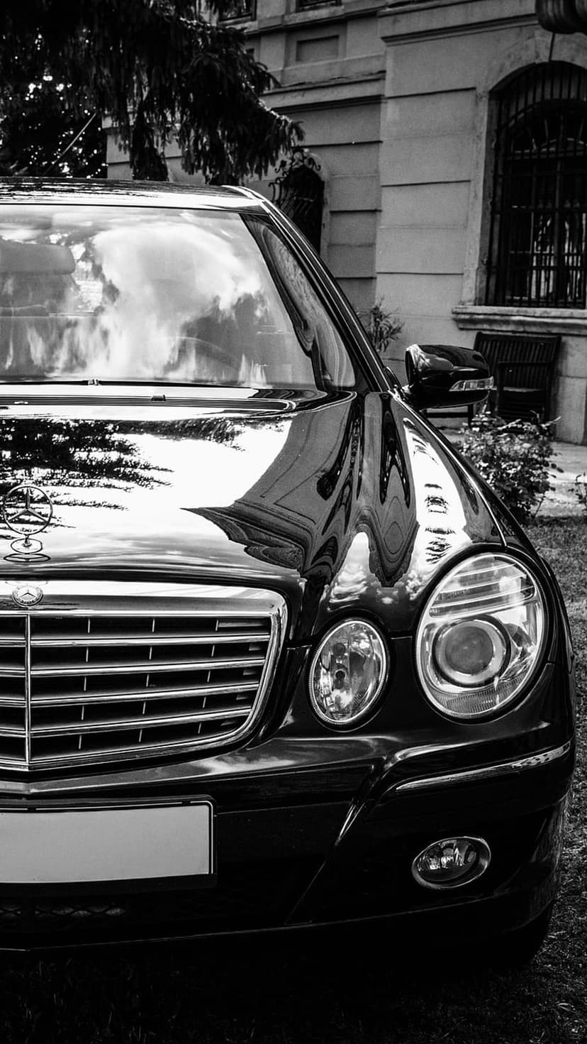Mercedes-Benz E-Class sedan front grille and chrome emblem in a high-contrast black and white car close-up shot.
