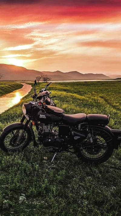 Royal Enfield Motorcycle by a Stream at Sunset
