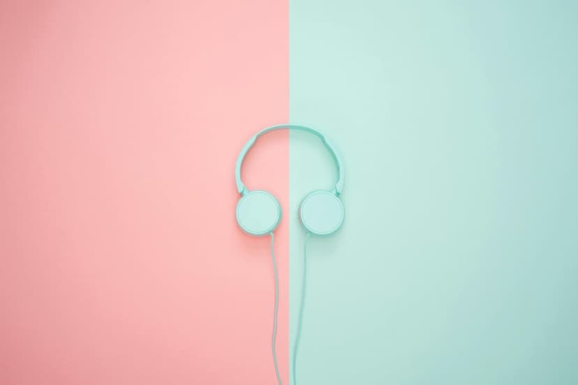 Blue minimalist headphones centered on a vertical split background of pastel pink and soft teal surfaces.