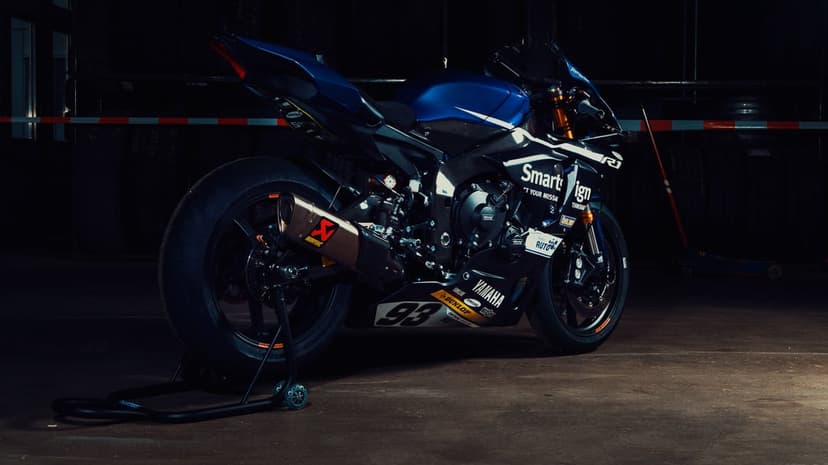 Blue Yamaha R1 motorcycle on a rear stand in a dark garage with carbon fiber parts and racing decals.