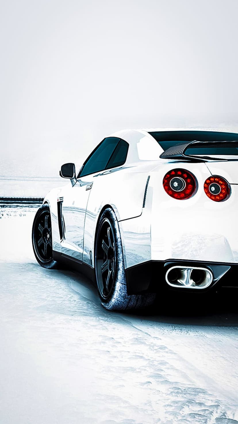 Nissan GT-R rear view with round red taillights and dual exhausts parked on a pristine white snow field.