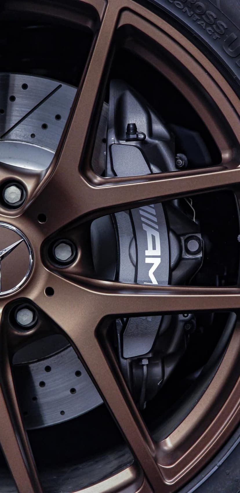Mercedes-AMG bronze alloy wheel and brake caliper featuring a silver finish and cross-drilled brake rotors.