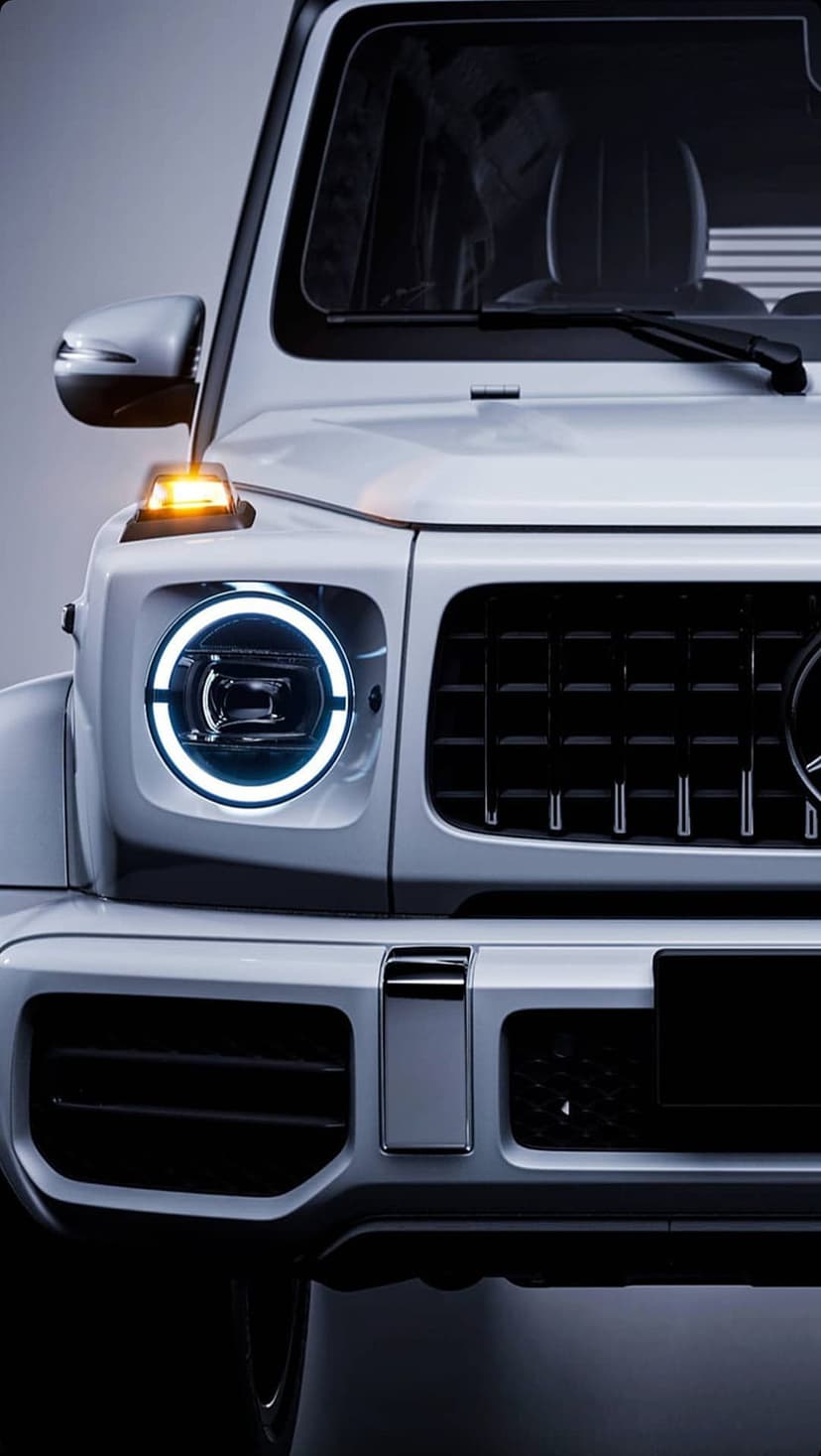 White Mercedes G-Class SUV highlights circular LED headlights and a black grille in a vertical close-up shot.