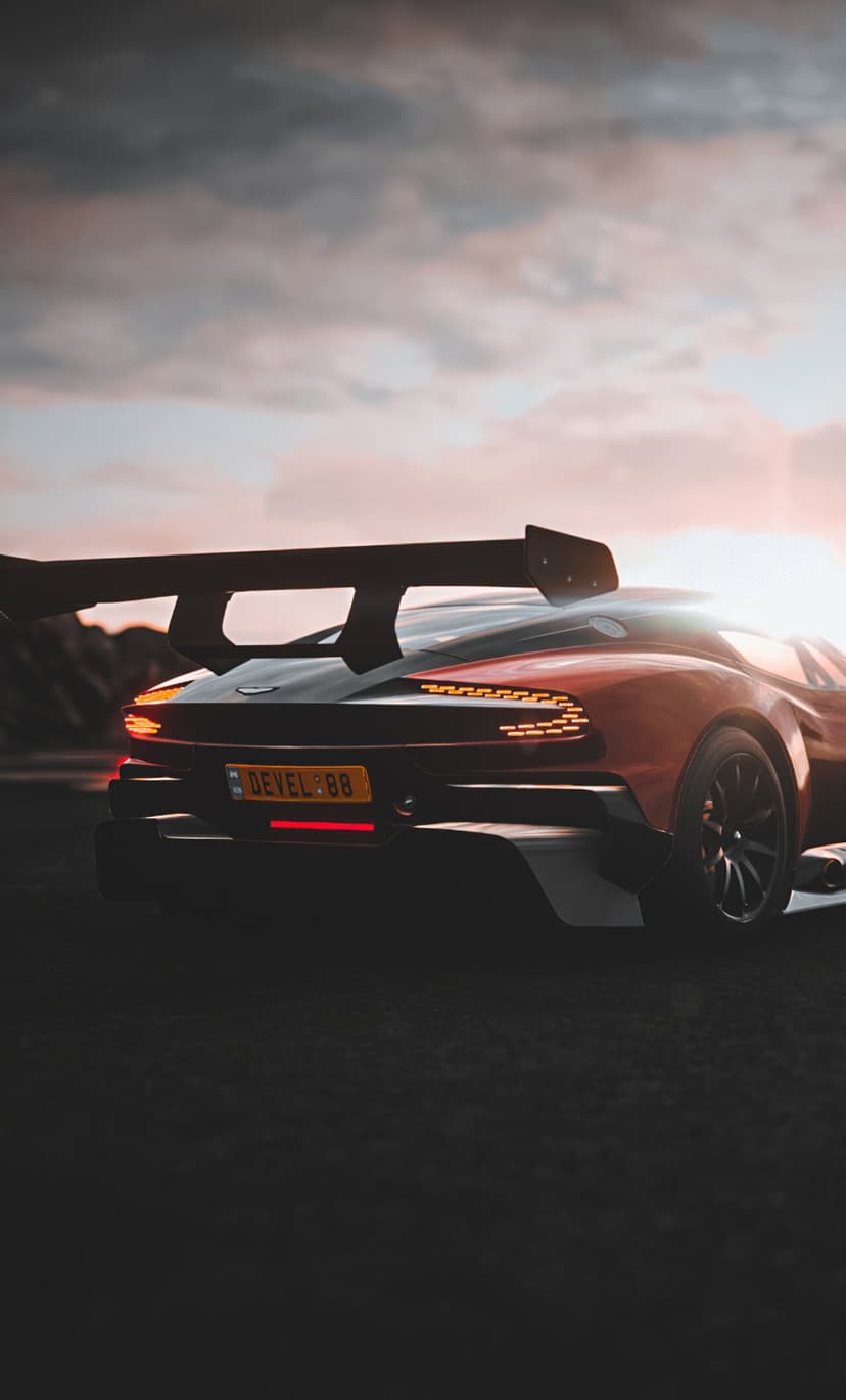 Rear view of a red supercar with a large wing and LED taillights under a warm sunset sky on a dark asphalt road.