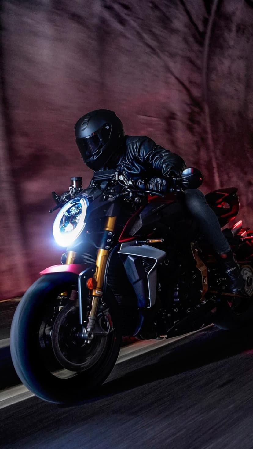 Motorcyclist in black leather steers a dark sportbike through a glowing tunnel with cinematic motion blur.