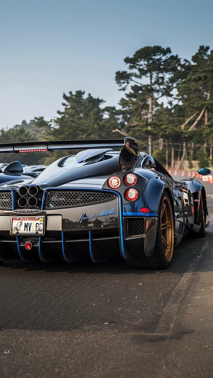 Pagani Huayra BC rear view featuring quad exhaust pipes, a carbon fiber diffuser, and blue paintwork on asphalt.