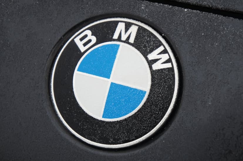 BMW logo featuring blue and white quadrants on a black ring against a dark textured metallic car surface.