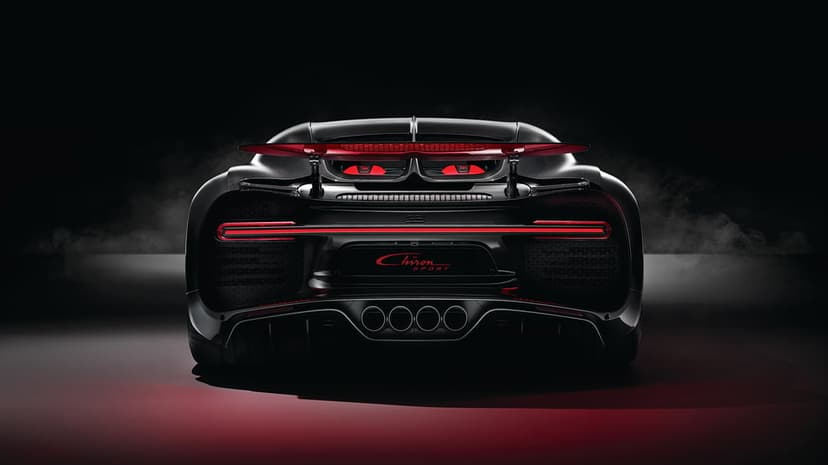 Rear view of a black Bugatti Chiron Sport hypercar with a glowing red LED light bar and quad exhaust in smoke.