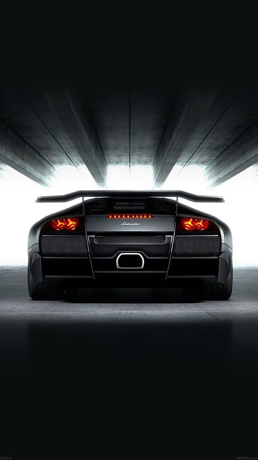 Matte black Lamborghini Murcielago rear view with glowing red taillights inside a dark industrial concrete tunnel.