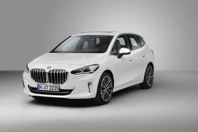 White BMW 2 Series Active Tourer with chrome grille and alloy wheels on a neutral gray studio background.
