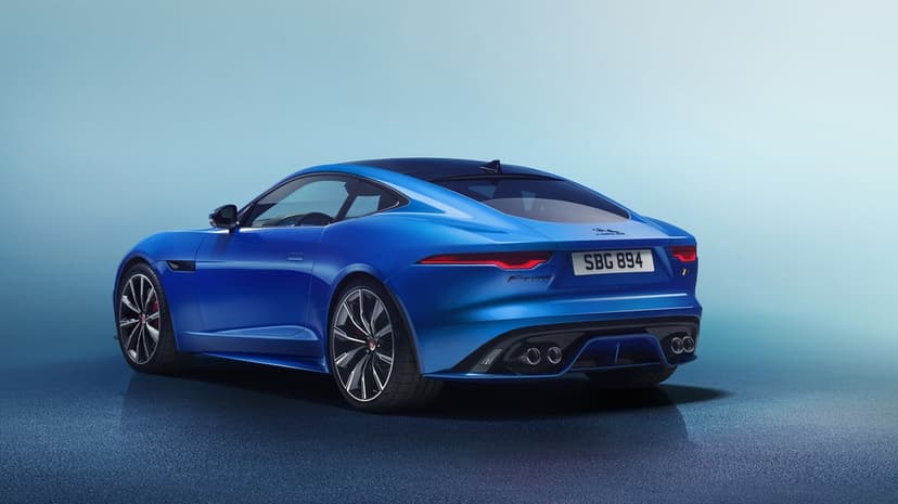 Blue Jaguar F-Type sports car with quad exhausts and slim taillights on a gradient blue background.