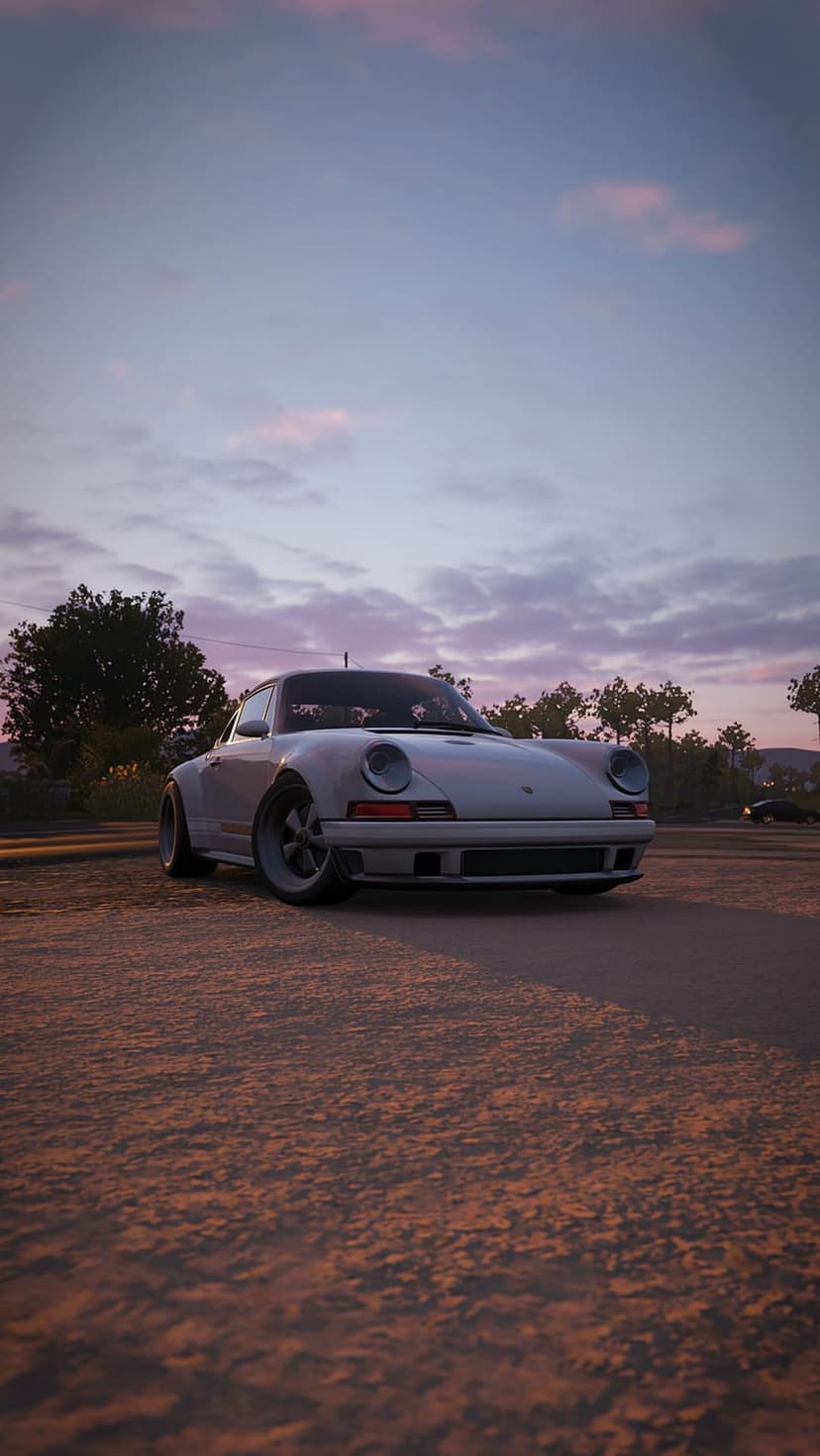 White vintage Porsche 911 parked on a dirt path beneath a vibrant purple and pink sunset sky with soft clouds.