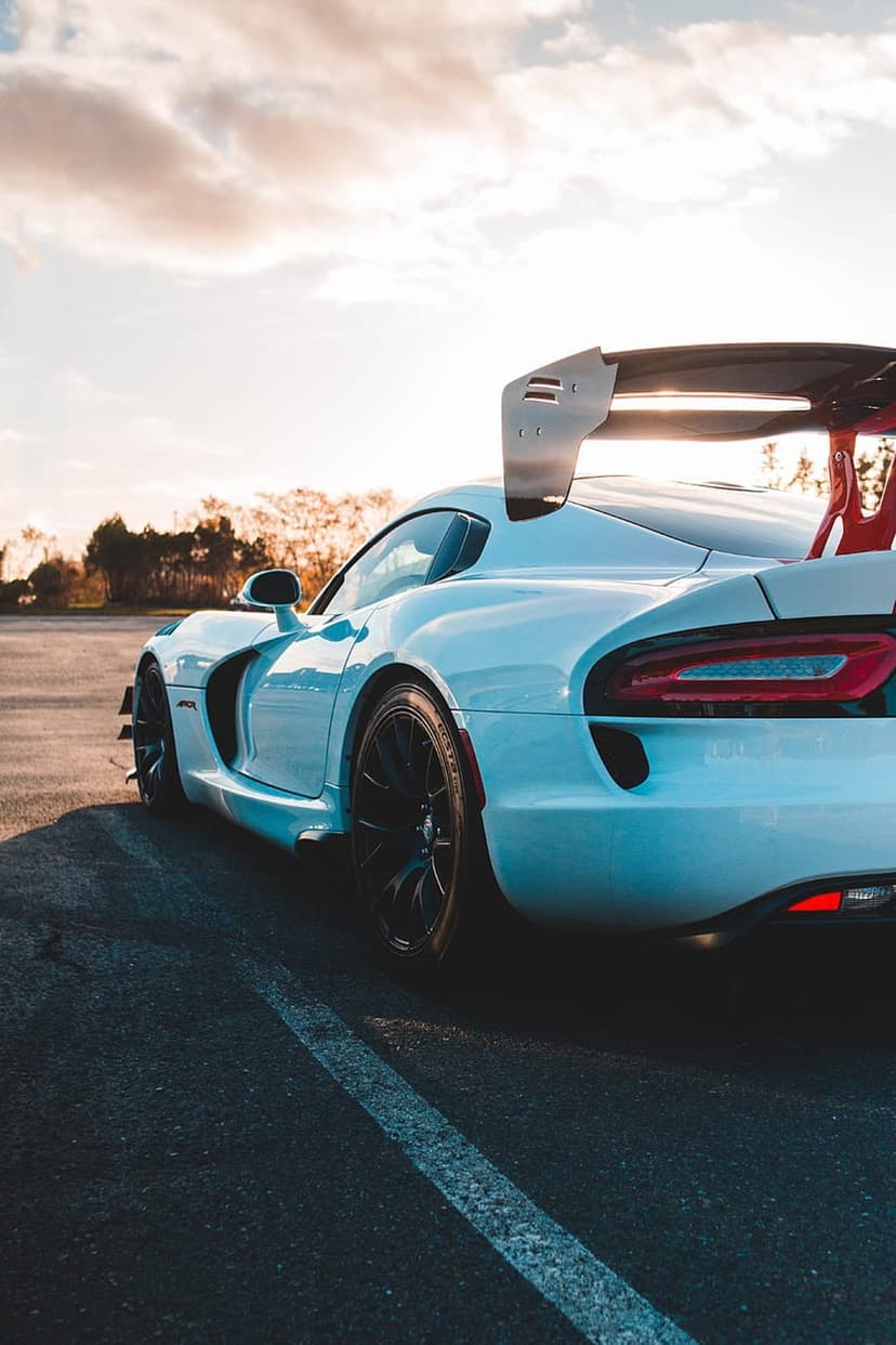 White Dodge Viper ACR with a large rear wing and red supports parked on asphalt during a golden hour sunset.
