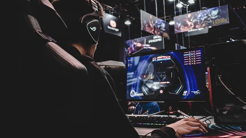 Gamer with a glowing ROG headset plays a first-person shooter on a monitor at a dark e-sports venue.