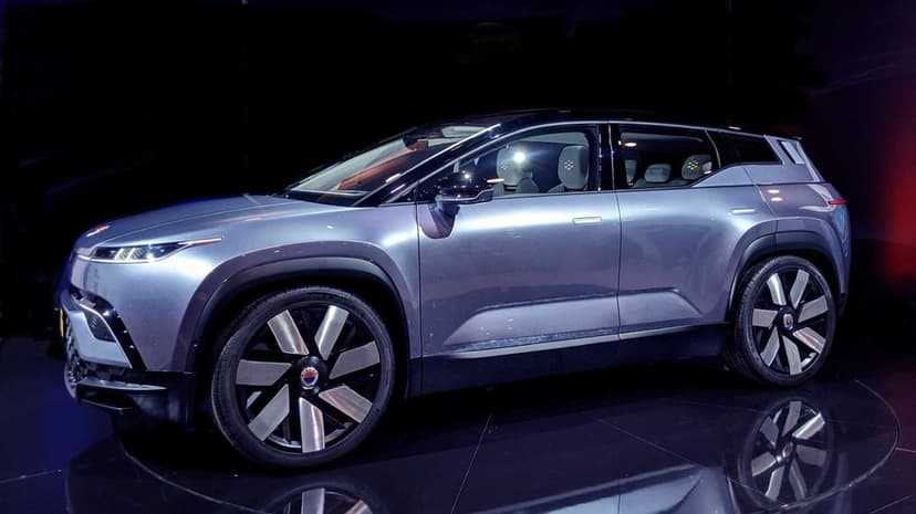 Silver electric SUV concept car on a reflective black floor with studio lighting and metallic finish.