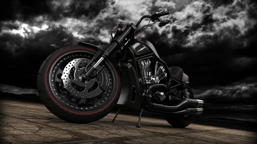 Black custom cruiser motorcycle with red pinstriped wheels parked on asphalt under dramatic dark storm clouds.