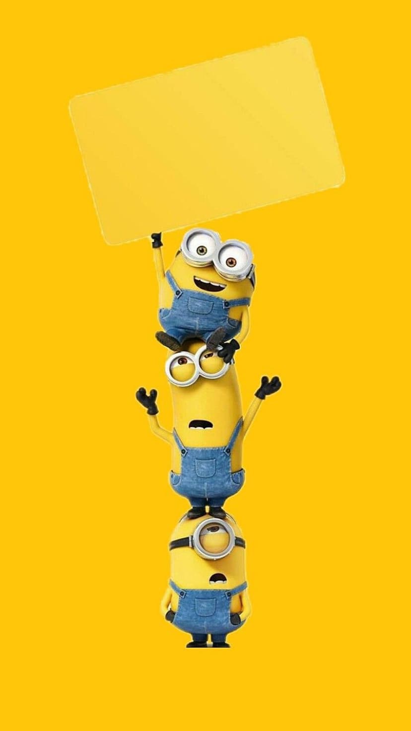 Three Minions in denim overalls stacked vertically against a yellow wall with the top one holding an empty sign.