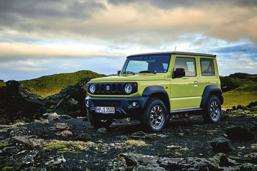 Lime green Suzuki Jimny parked on a rocky mossy landscape under a soft sunset sky in an off-road scene.
