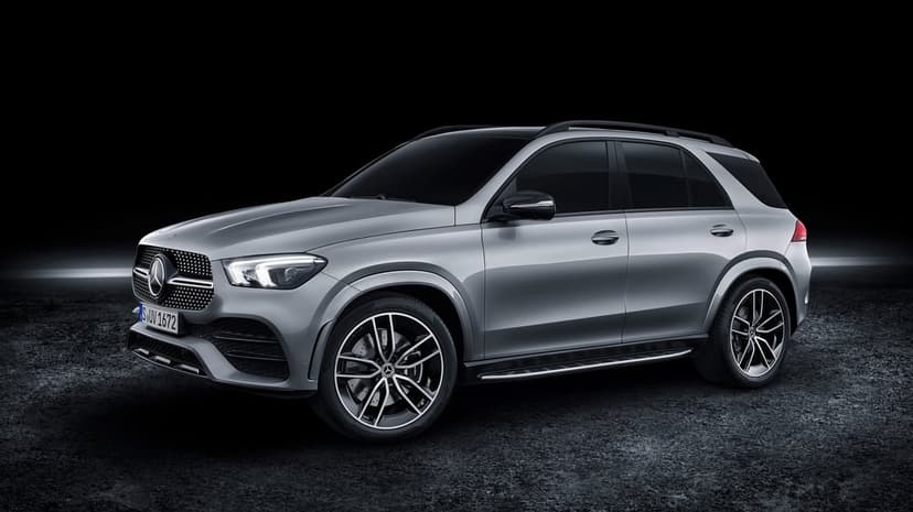 Silver Mercedes-Benz GLE SUV parked on a dark textured surface against a black studio backdrop with rim lighting.