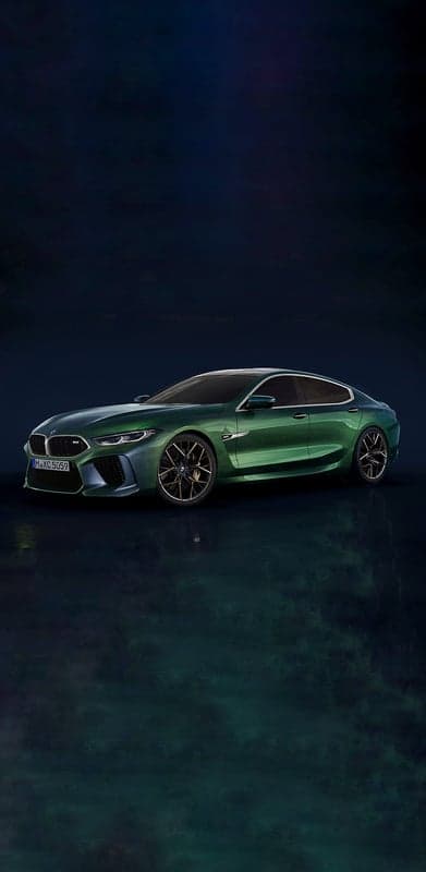 Sleek green BMW M8 Gran Coupe on dark reflective surface