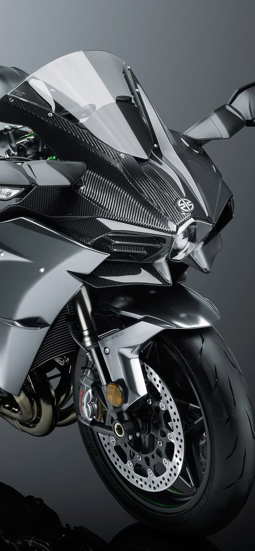 Kawasaki Ninja H2R front fairing with carbon fiber weave, aerodynamic wings, and sharp LED headlights close-up.