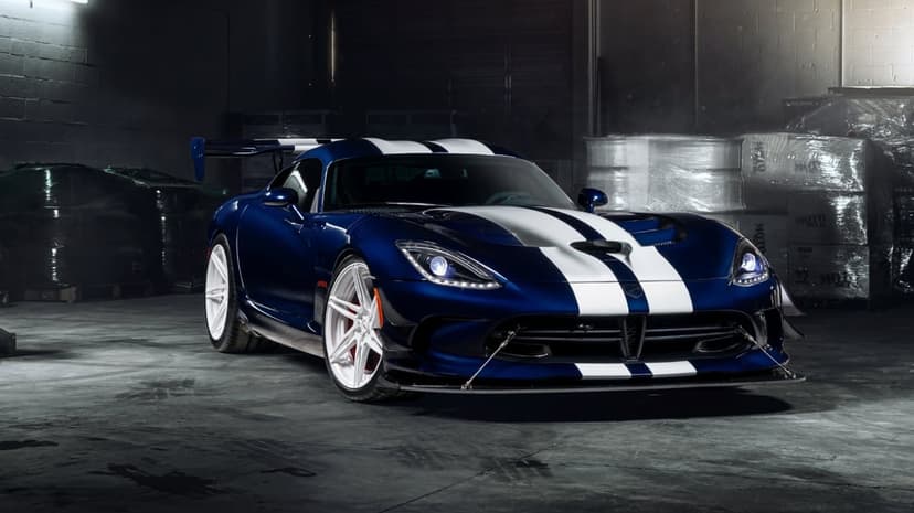 Blue Dodge Viper ACR with white racing stripes parked in a dark industrial warehouse with cinematic lighting.