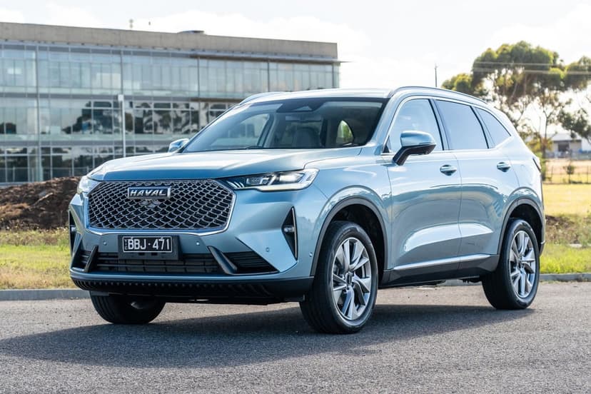 Light blue Haval H6 SUV parked on asphalt in front of a modern glass office building under a clear sky.