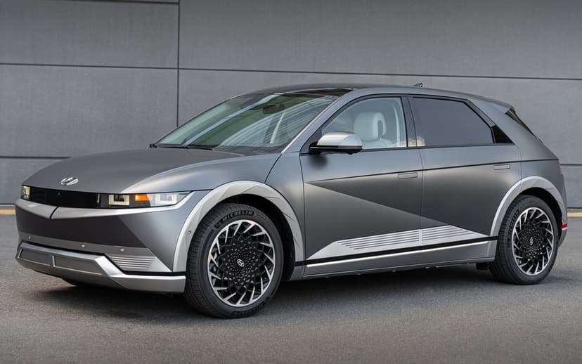 Matte grey Hyundai IONIQ 5 electric vehicle with intricate geometric wheels against a grey textured wall.