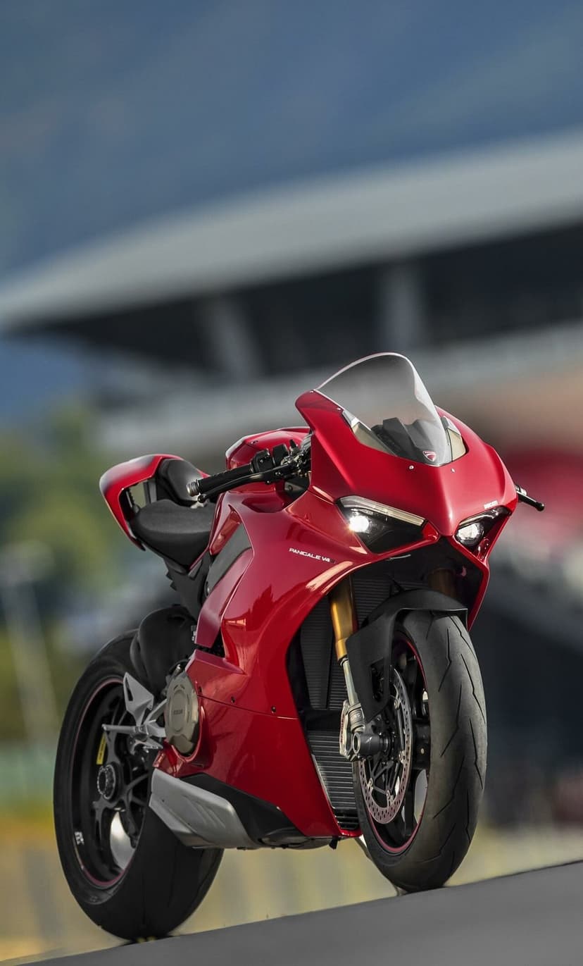 Red Ducati Panigale V4 sportbike on a racing track with LED headlights and gold forks in a portrait view.