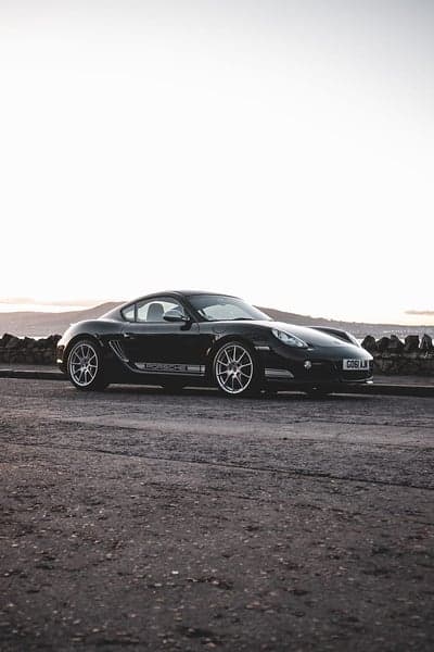 Black Porsche Cayman S Coastal Road Mobile Wallpaper