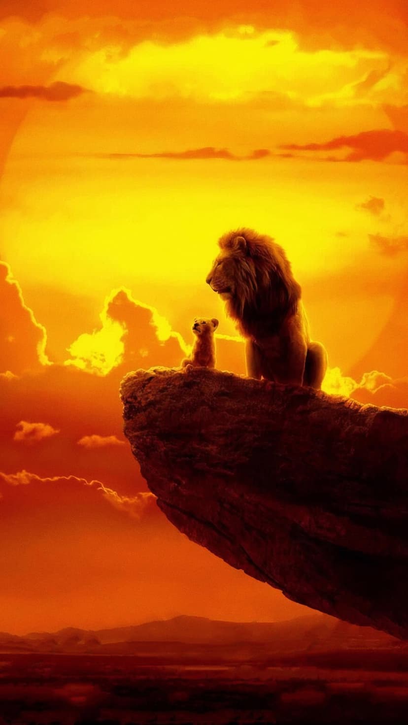 Adult lion and small cub silhouetted on a rocky cliff edge against a vibrant orange and yellow sunset sky.