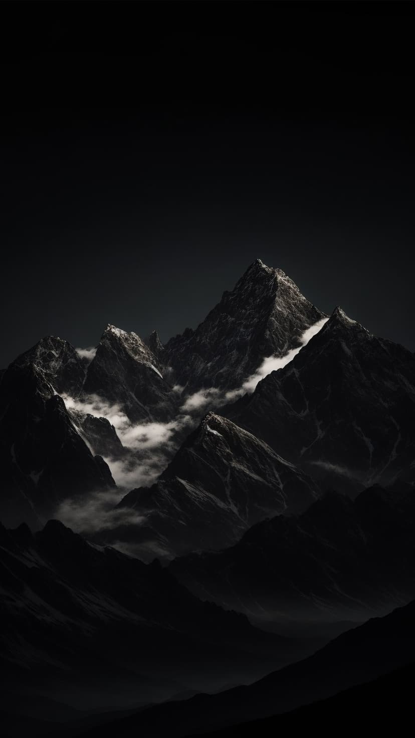 Jagged dark mountain peaks covered in patches of snow are surrounded by wispy gray clouds and thick mist.