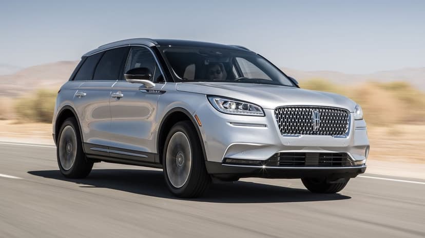 Silver Lincoln Corsair SUV driving on a desert highway under a clear sky with motion blur and sun reflections.