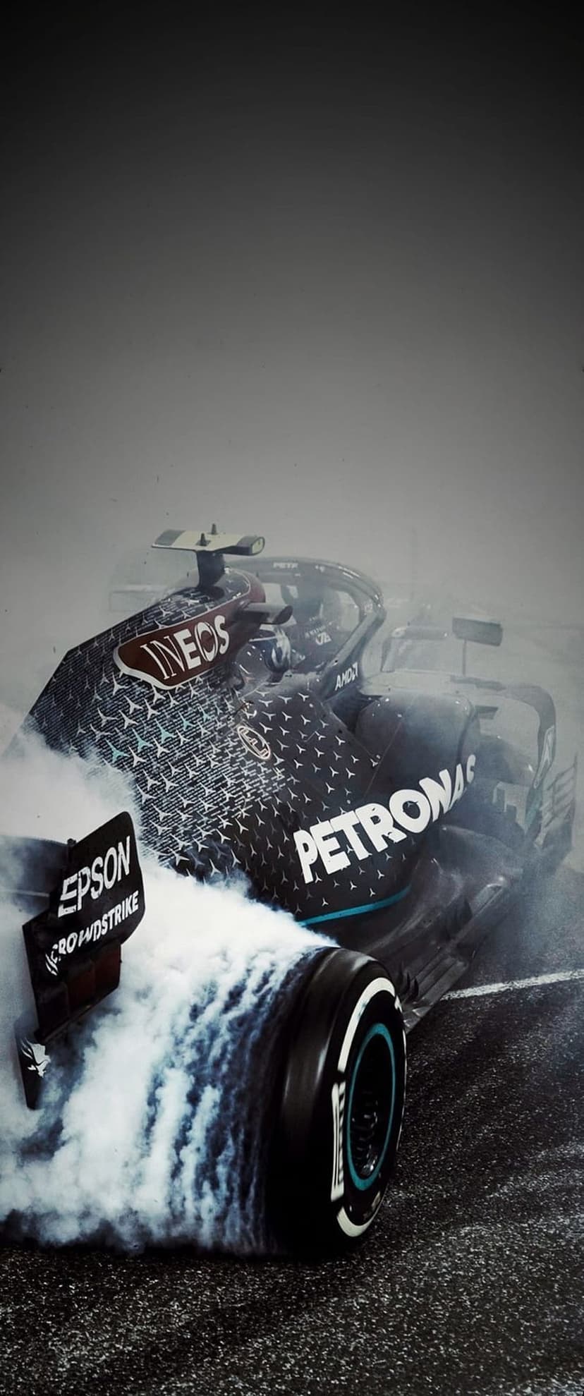 Mercedes-AMG Formula 1 car spinning its tires in a thick cloud of white smoke with Petronas logos clearly visible.