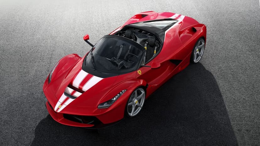 Red Ferrari LaFerrari Aperta with white racing stripes on a gray asphalt surface, showing its sleek open-top design.